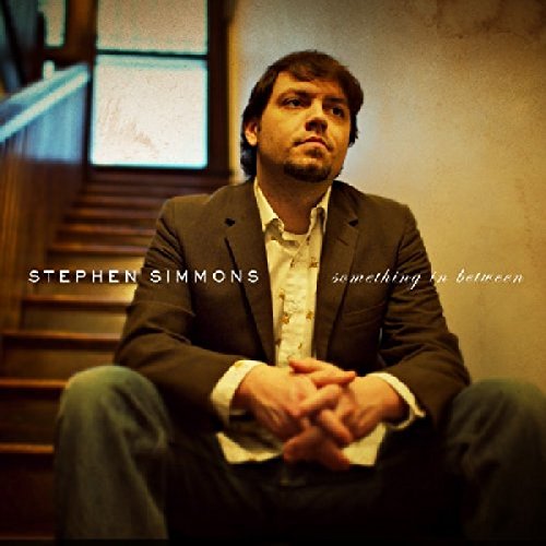 "Album cover featuring a man sitting on stairs, wearing a suit jacket and jeans."