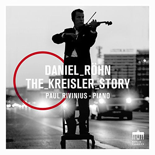 Black and white image of a man playing violin on a chair, cityscape behind.