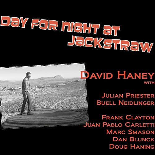 "Album cover with man standing on a cliff, black background, red text."