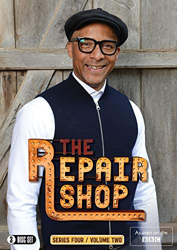 Jay Blades wearing a cap and glasses in front of a wooden wall background.