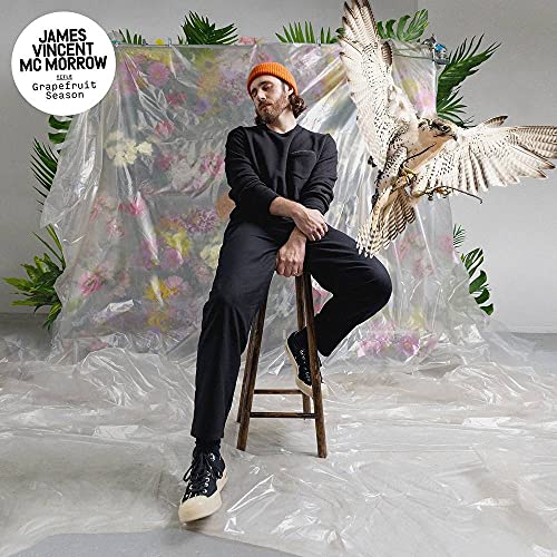Man with a hawk, tropical plants, and plastic sheeting backdrop.