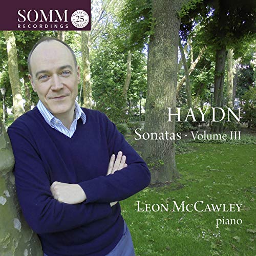 Man in navy sweater stands by tree in wooded area, CD cover art.