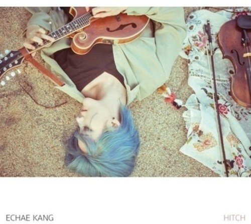 Person with blue hair lying with a guitar and violin.