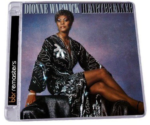 "Dionne Warwick sitting on a velvet surface, wearing a black dress with white patterns."