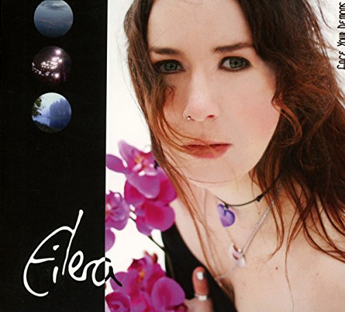 A woman with long brown hair and purple necklace surrounded by pink flowers.