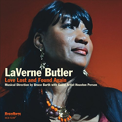 "Album cover featuring a woman with dark hair, beaded jewelry, and red background."