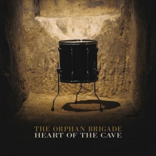 "Album cover with a drum in a cave, text 'The Orphan Brigade Heart of the Cave'."
