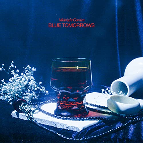 Album cover: a glass with red liquid, flowers, and a doily.
