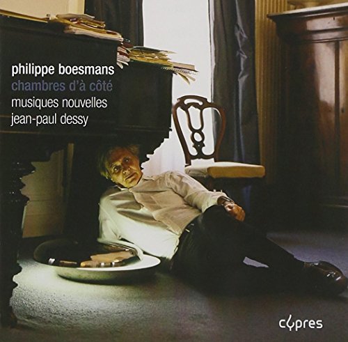 Man lying on the floor beside a piano, with sheet music and a chair nearby.