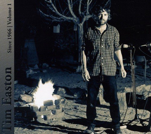 "CD cover with a man standing by a campfire and microphone."