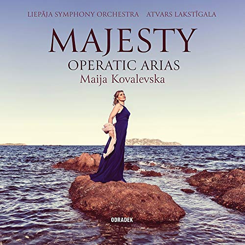 "Album cover featuring a woman in a blue dress standing on a rocky shoreline."