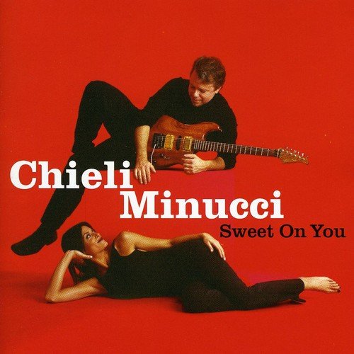 "Album cover with a man playing guitar and a reclining woman on red background."