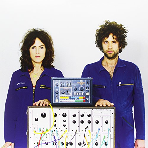 "Album cover featuring a man and woman standing behind an electronic device."