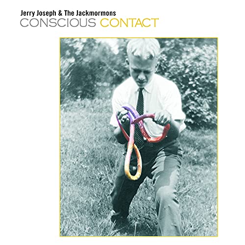 Black and white photo of a boy holding a colorful snake in a field.
