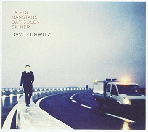 CD cover with a man walking on a highway, vehicles nearby.
