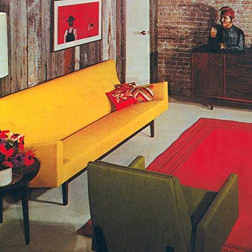 Vintage room with yellow sofa, red rug, and artwork on the wall.