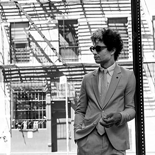 Black and white portrait of Jose James in a suit and sunglasses.