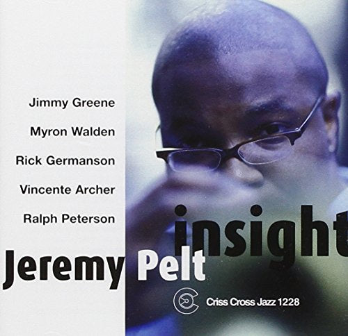 "Album cover with a close-up of a man wearing glasses, text on the left."