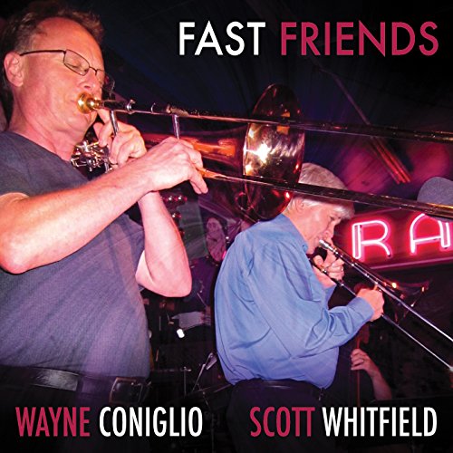Two musicians playing trumpet and trombone on a dimly lit stage.