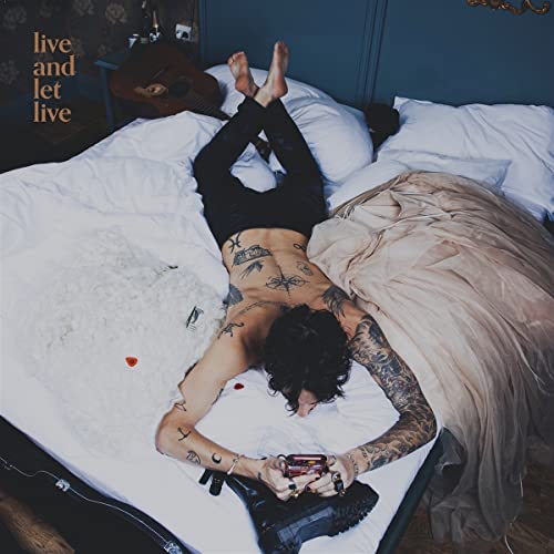 Album cover: tattooed person lying on a bed, feet up.