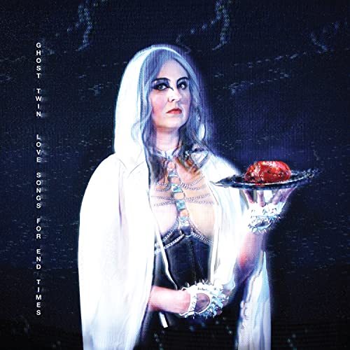 Woman in white holds a heart-shaped object, dark and moody lighting.
