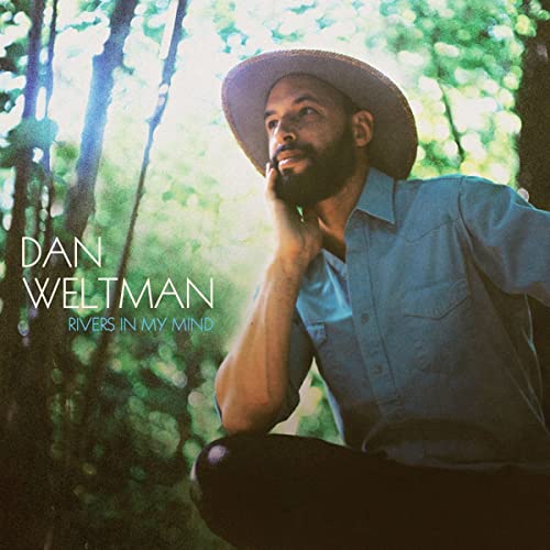 CD cover featuring a man in a hat amongst trees.