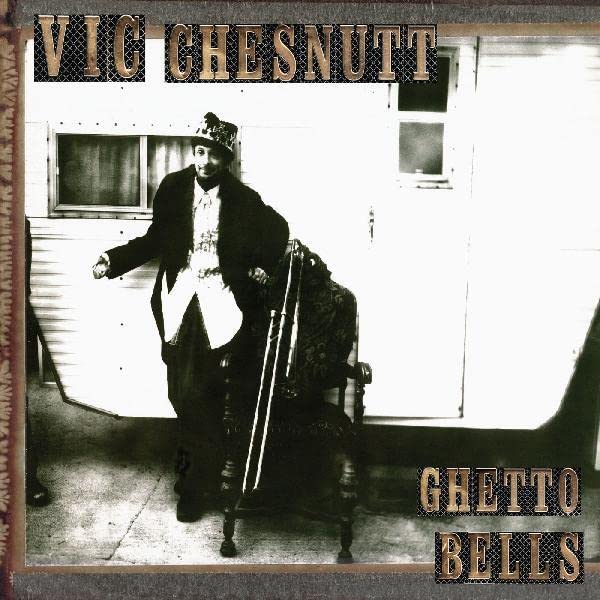 Black and white portrait of Vic Chesnutt seated in an ornate chair.