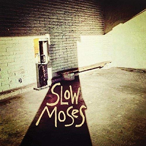 "Album cover with 'Slow Moses' written on a dark red carpet in a dimly lit room."