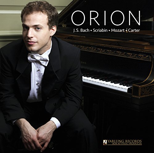 Man in a tuxedo sits beside a grand piano, album cover in the background.