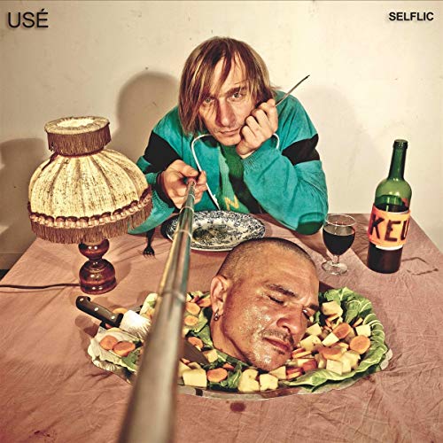 A man eats a severed head on a plate with a fork and knife.