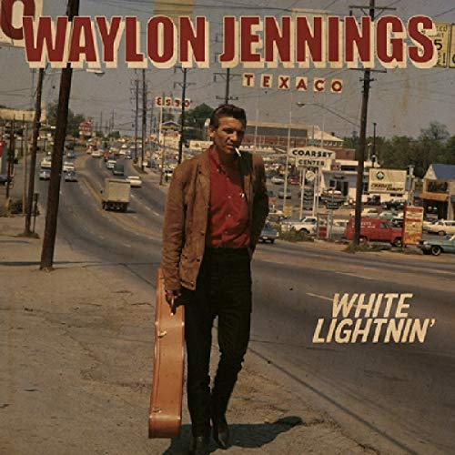 "Album cover featuring Waylon Jennings holding a guitar case on a street."