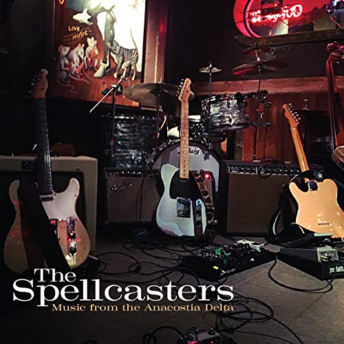 "CD cover featuring three electric guitars on stage with drums and amplifiers."