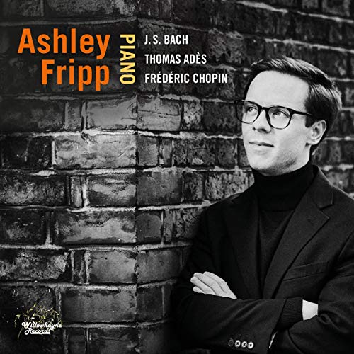 Man in suit and glasses stands against brick wall on album cover.
