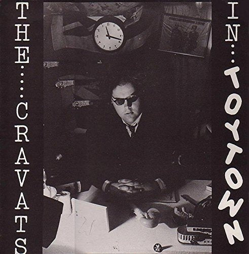 Black and white vinyl album cover with a man sitting at a cluttered desk.