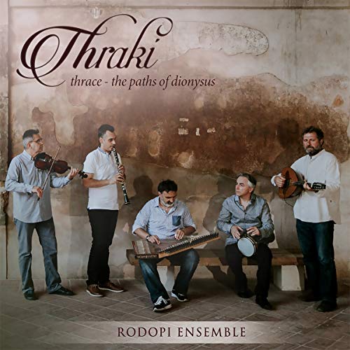 Five musicians with traditional instruments sit against a textured wall.