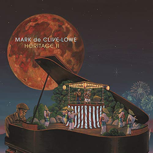 A man plays a grand piano topped with a traditional Japanese festival stage at night.