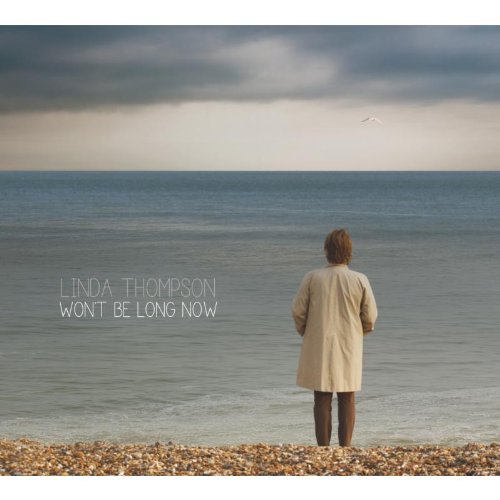 Album cover: woman in beige coat standing on a rocky beach, facing the sea.