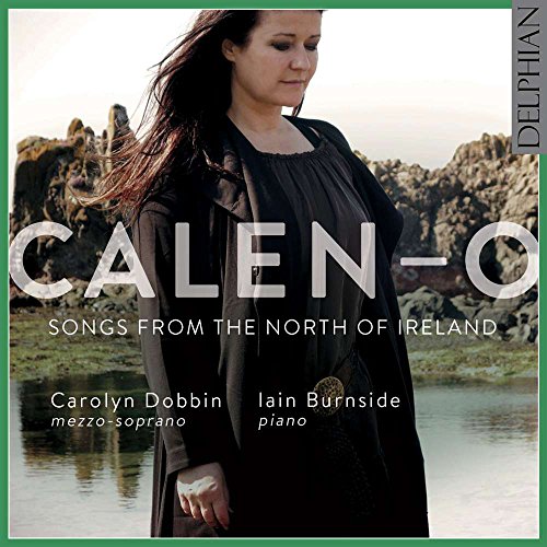 CD album cover featuring a woman in black standing by a rocky lake.