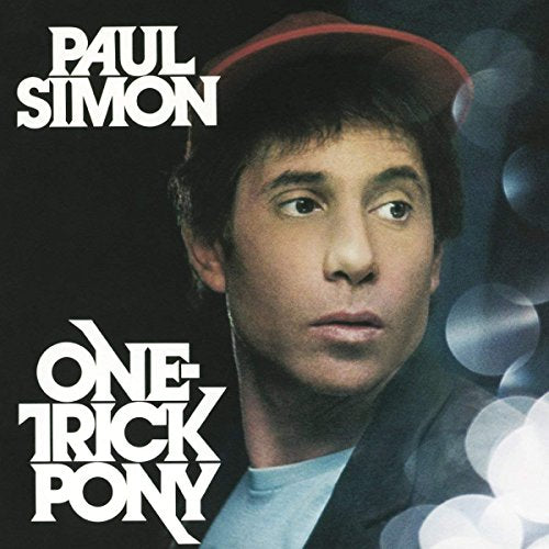 "Paul Simon's album cover featuring a man in a red cap against a dark background."