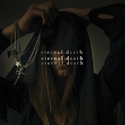 A woman in dark clothing and jewelry obscures her face with her hair.