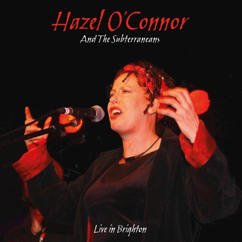 Hazel O'Connor singing into a microphone on a dark red background.