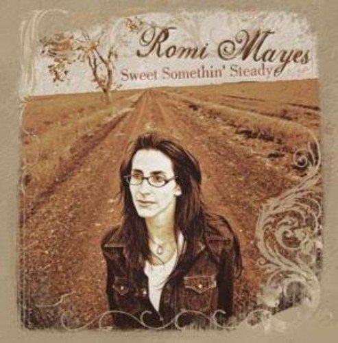 "Album cover with a woman standing in a field, sepia-toned with ornate design."