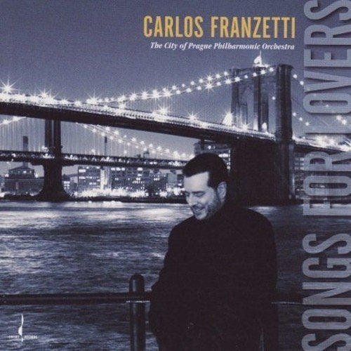 "CD cover with a man standing by a lit bridge at night."