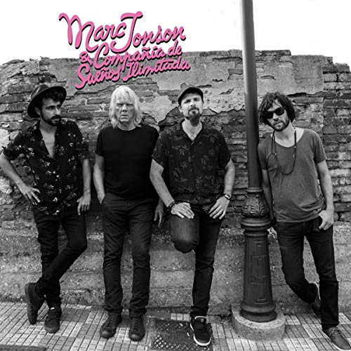 "Black and white vinyl album cover with four men standing by a brick wall."