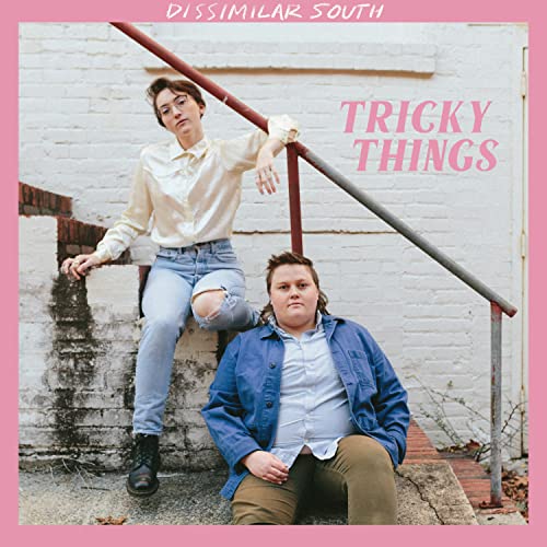 Two people posing on steps in front of a white brick wall.
