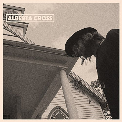Black and white album cover featuring a person in a hat and building.