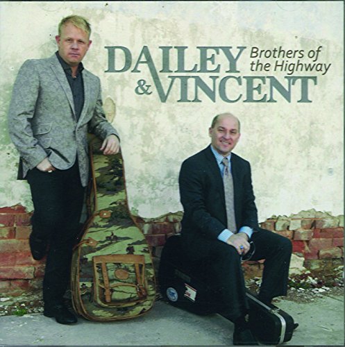 "Album cover featuring two men in suits with guitar cases, against a worn wall."