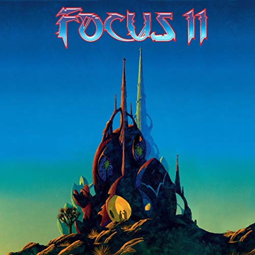 The image depicts a fantastical, futuristic structure with a large, central spire and several smaller, pointed protrusions. The structure is dark brown and appears to be made of a metallic or crystalline material. It is situated on a rocky outcropping, with a few sparse plants or trees nearby. The background of the image is a gradient of blue and green, suggesting a futuristic or otherworldly setting. Alt text: "Vinyl album cover featuring a futuristic, metallic structure with
