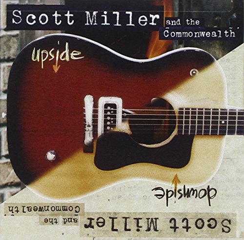 "Album cover featuring a brown and beige guitar against a brick wall background."