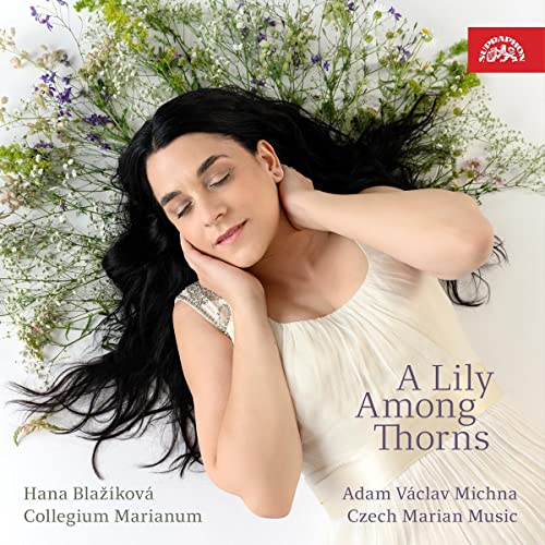 Woman with dark hair lying among white and purple flowers.